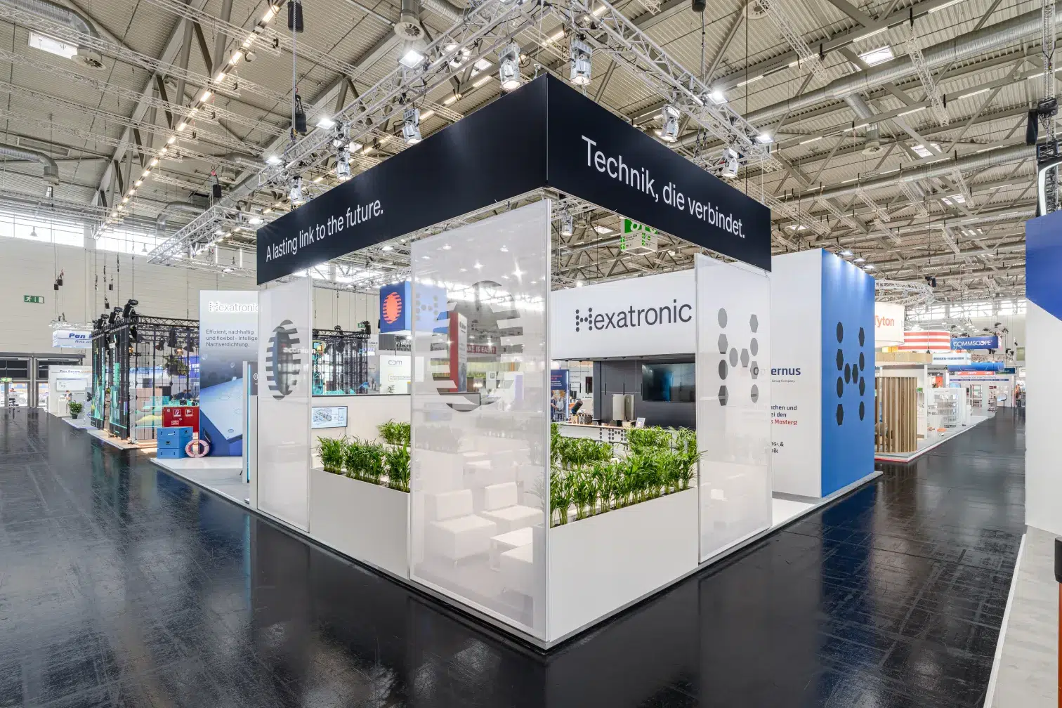 Messebau Köln – Hexatronic und Opternus Gemeinschaftsstand mit klarer Architektur und Pflanzen-Design auf der AngaCom 2025.
