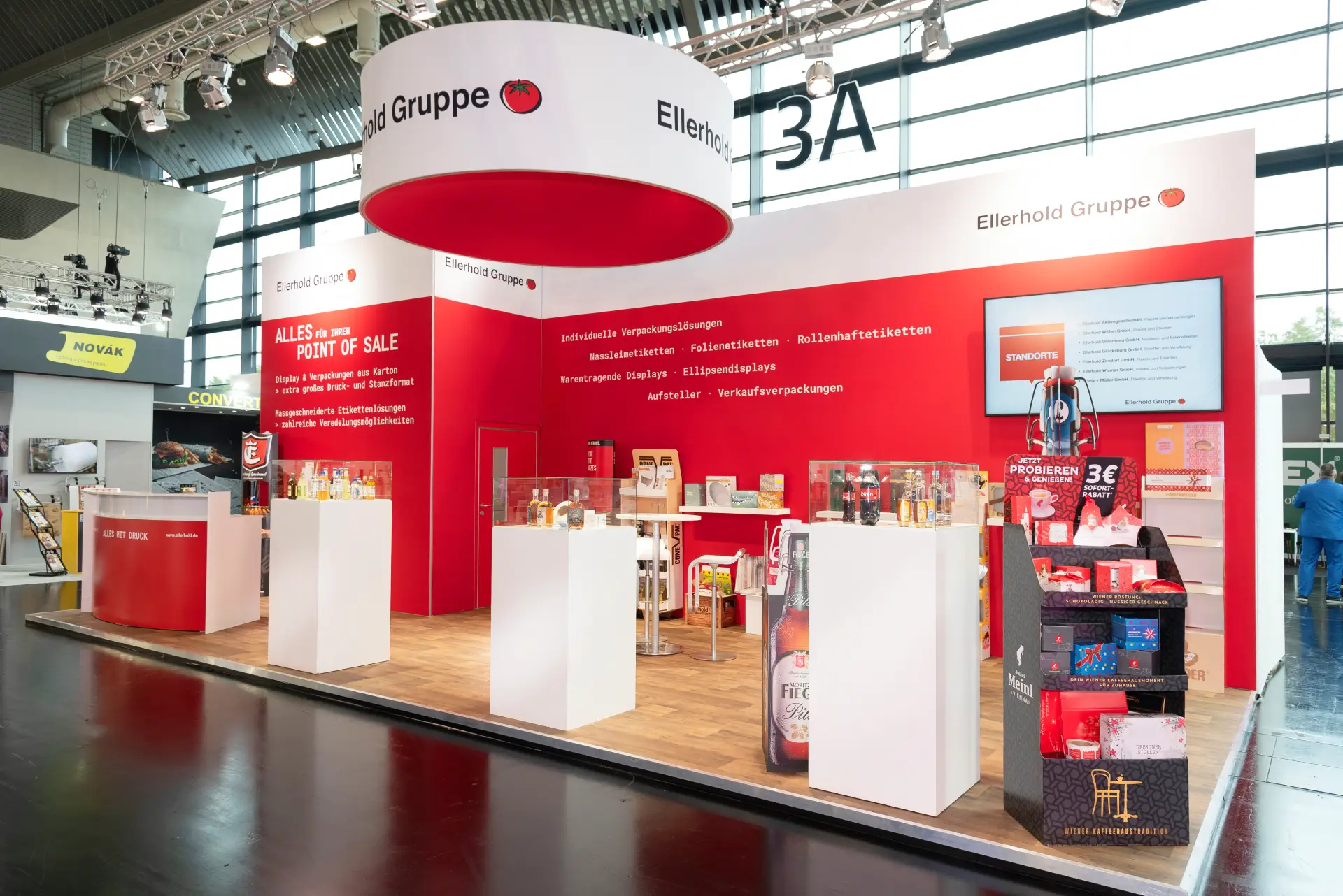 Moderner Messestand der Ellerhold Gruppe auf der FachPack 2025 in Nürnberg mit roten Wänden und Verpackungslösungen am Point of Sale – kreativer Messebau Nürnberg.