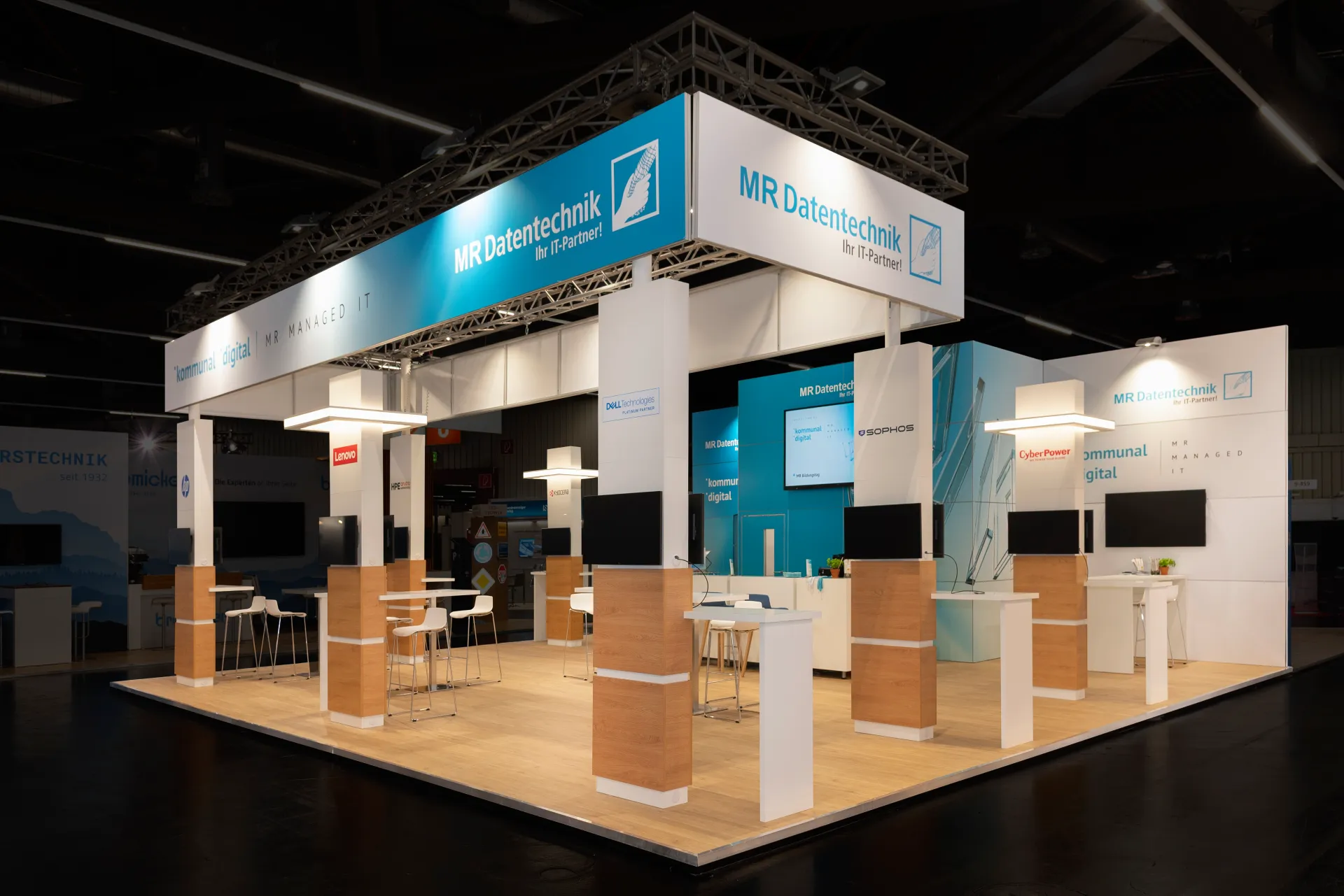 Offener Messestand von MR Datentechnik Ihr IT-Partner mit holzverkleideten Säulen, Stehtischen, Monitoren und Partnerlogos wie Dell, Lenovo und Sophos.