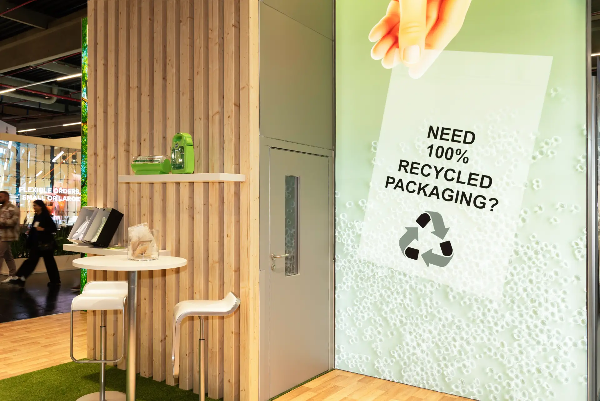 Übersicht des Micro-Pak Messestands auf der FachPack 2025 mit Holz- und Graselementen, grünem Design und 100 % recycelter Verpackung – Messebau Nürnberg.
