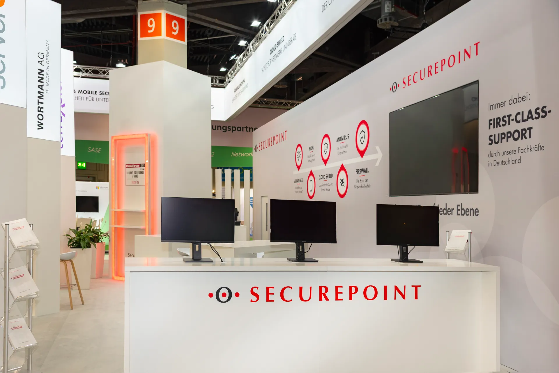 Innenbereich des Securepoint Messestands mit Bildschirm, Sitzmöbeln und einem YAW-Motion-Simulator für Messebesucher auf der it-sa 2025.