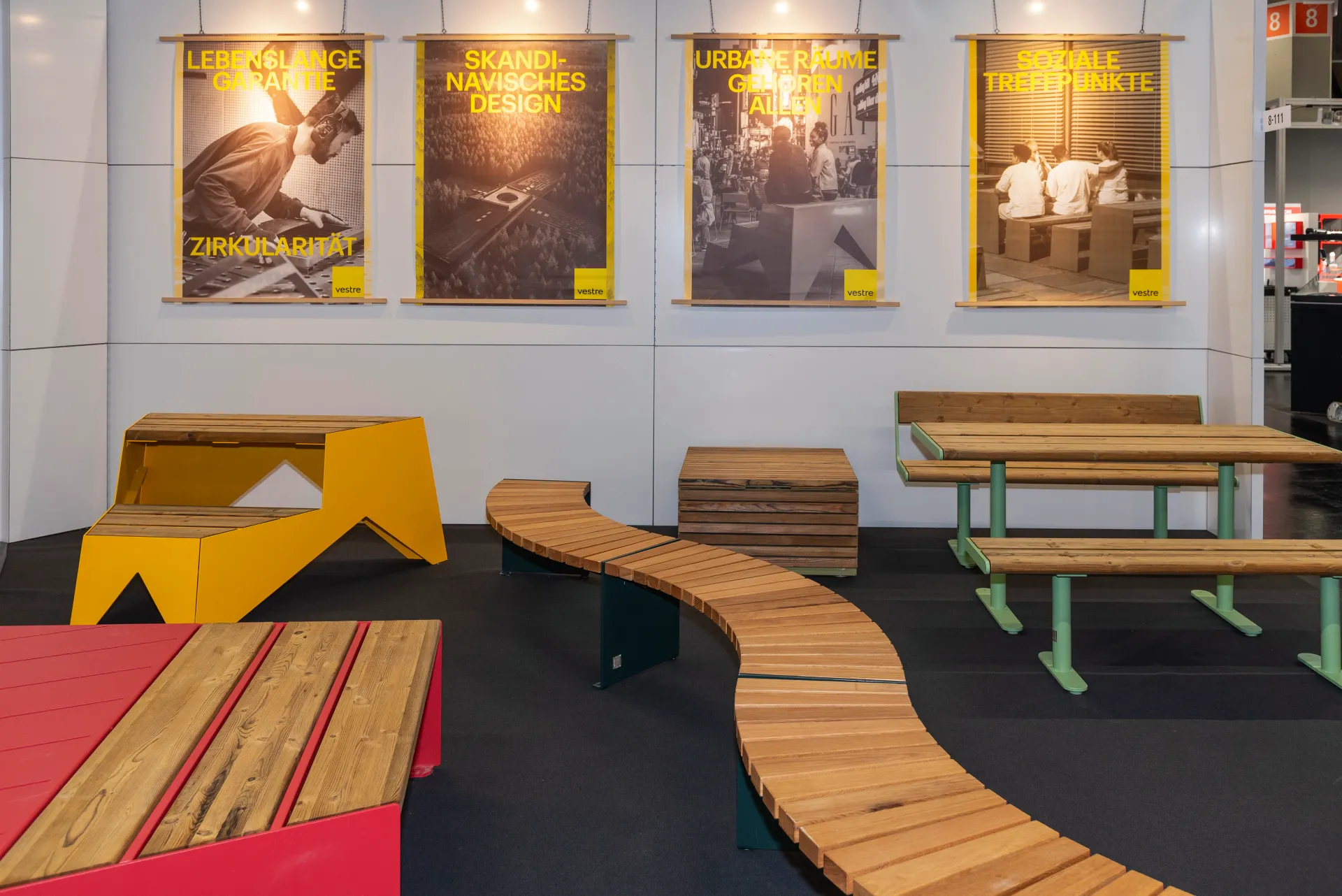 Vestre-Loungebereich auf der Kommunalmesse Nürnberg mit geschwungenen Holzbänken, gelbem und rotem Mobiliar und gelben Plakaten zu Skandinavischem Design und sozialen Treffpunkten