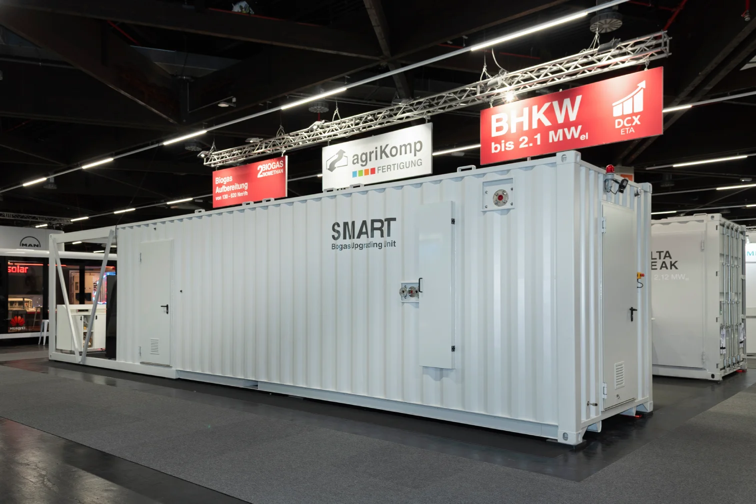 Weißer Container-Messestand von agriKomp mit der Aufschrift SMART Biogas Upgrading Unit und rotem BHKW-Banner bis 2,1 MW in einer Messehalle in Nürnberg.