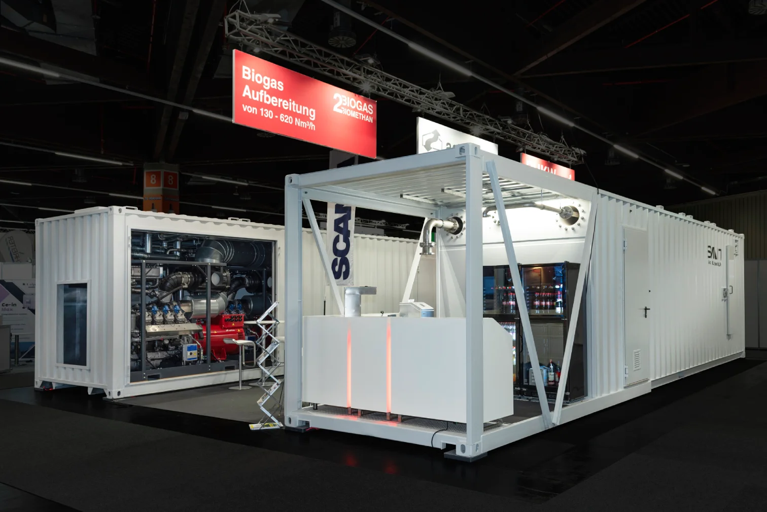 Weiße Container als Messestand für die Biogas-Aufbereitung von agriKomp in Nürnberg, mit sichtbarer BCS-Anlagentechnik und beleuchteter roter Beschriftung Biogas-Aufbereitung von 100 bis 500 Nm³/h.